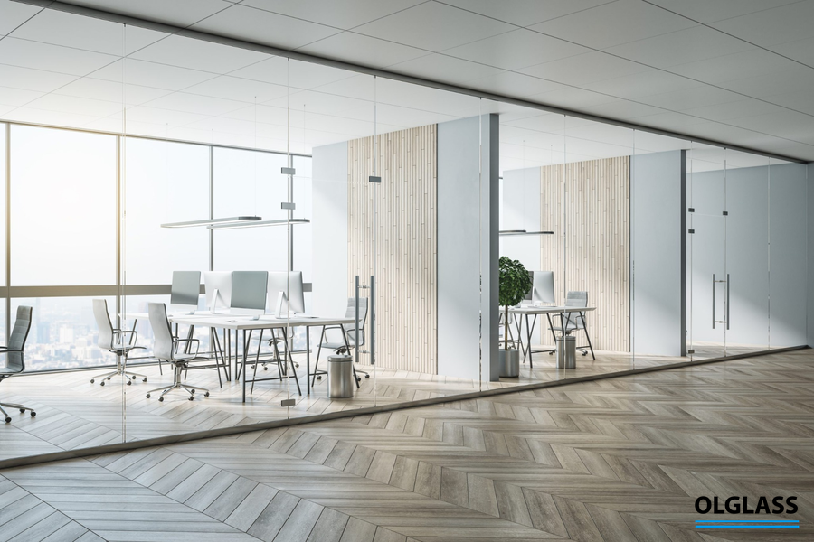 Biurowy korytarz z przeszklonymi gabinetami, w których zastosowano czarne profile i duże tafle szkła.