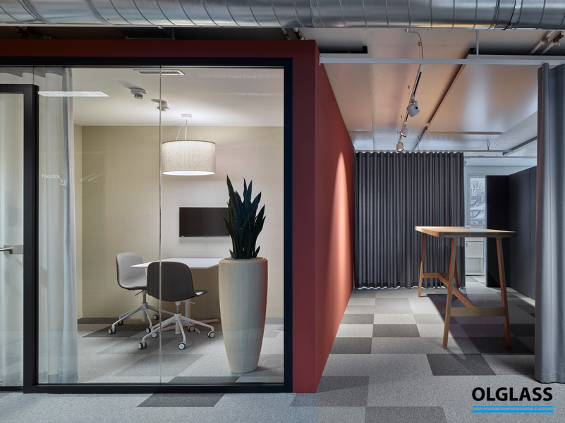 Mały pokój spotkań za ścianką szklaną z krzesłami i rośliną w dużej donicy.