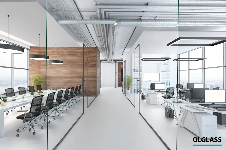 Przeszklona sala konferencyjna z długim stołem i krzesłami, widoczna przez duże tafle szkła.