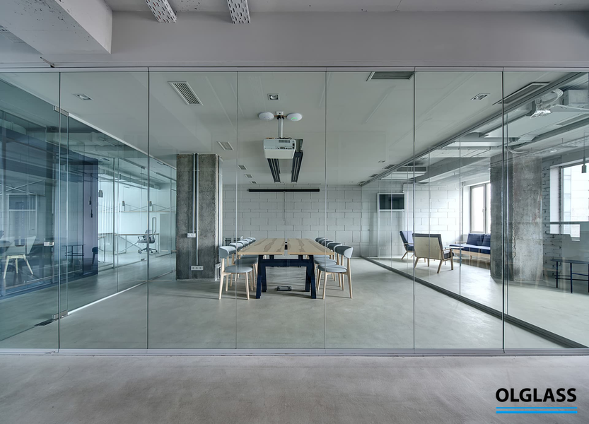 Przeszklona sala spotkań z przyciemnianym szkłem, w której widać krzesła i stolik konferencyjny.